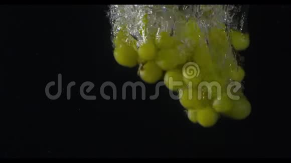 一串绿色的葡萄在镜头左侧潜入水中黑色背景慢动作米秒视频的预览图