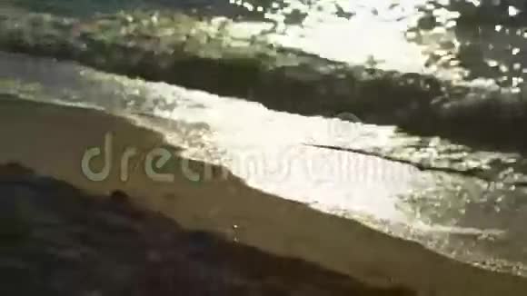 海水在黄日落的灯光下冲刷沙滩平静的冲浪图像视频的预览图