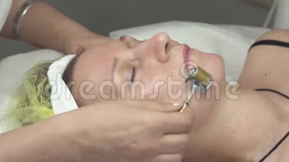 美容师在美容院用滚筒做女人的电疗面视频的预览图