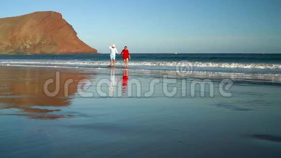 恋爱中的夫妻无忧无虑地从海滩上的水中散步加那利群岛特内里费海岸图片视频的预览图