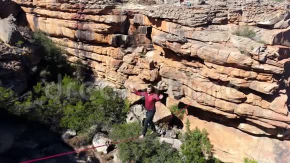 男子乘坐绳索在岩石山脉上行走4k视频的预览图