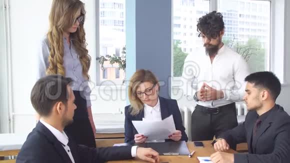 一群年轻商人在办公室的谈判桌上同事翻阅文件视频的预览图
