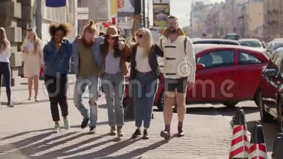 一群年轻时髦的朋友在街上散步互相拥抱着日落的太阳耀斑视频的预览图
