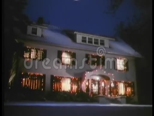 在装饰在圣诞灯光下的房子上空盘旋的满月镜头视频的预览图