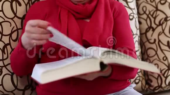 坐在沙发上翻着大书页的老妇人视频的预览图