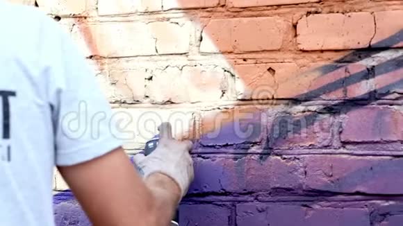 一个带着一罐油漆的年轻人在墙上涂鸦一手特写视频的预览图