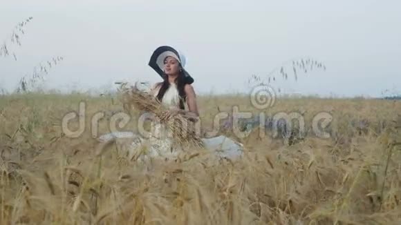 穿着白色连衣裙戴着小麦地帽子的黑发女孩视频的预览图