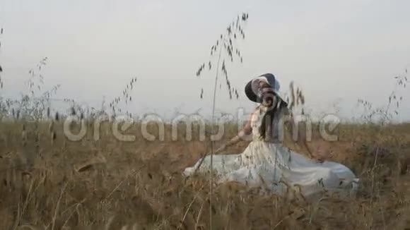 穿着白色连衣裙戴着小麦地帽子的黑发女孩视频的预览图