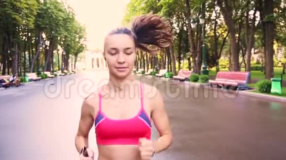 美丽的年轻模特女孩在公园里跑步慢动作视频的预览图
