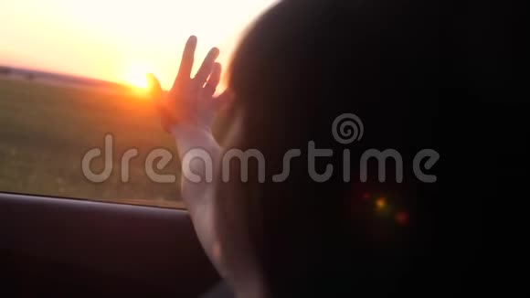 路旅游出行理念女孩在窗外挥舞着她的手阳光下的风在汽车慢动作视频中生活方式视频的预览图