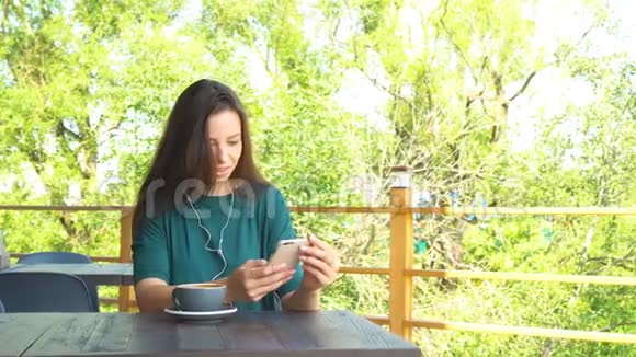 有智能手机的女人在咖啡馆里喝着咖啡微笑着在手机上发短信美丽少女的肖像视频的预览图