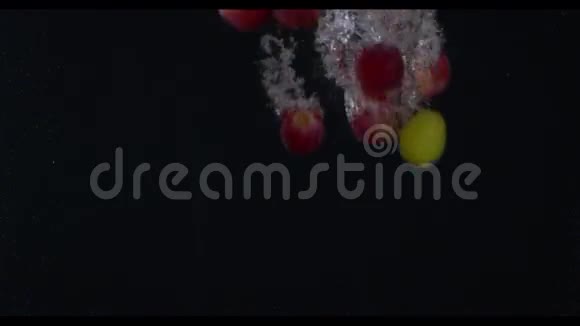 红葡萄和绿葡萄在镜头中央潜入水中黑色背景慢动作ms视频的预览图