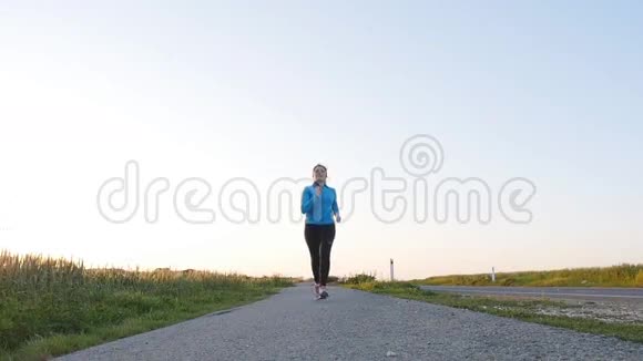 年轻女子跑在日出路上健身理念视频的预览图