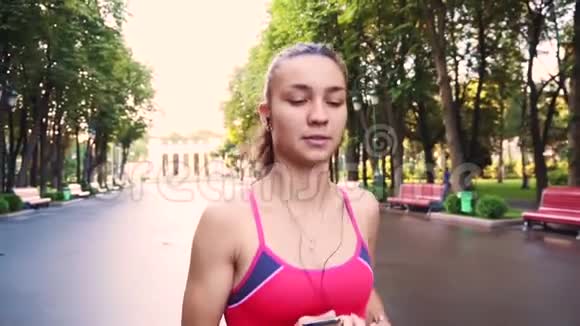 美丽的年轻模特女孩在公园里跑步慢动作视频的预览图