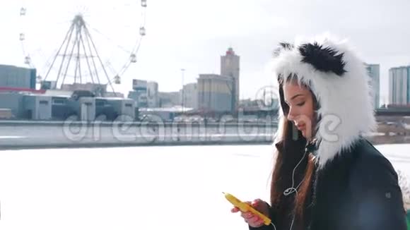 一个戴着熊猫帽的女孩在城里听音乐视频的预览图