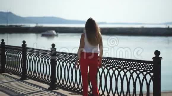 美丽的年轻女子走在码头上视频的预览图