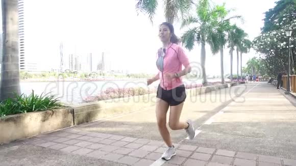 慢动作年轻的亚洲女人早上在人行道上跑步年轻的亚洲运动女子在公园里跑步视频的预览图