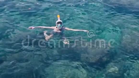年轻女子穿着白色泳衣在蓝色热带海水中浮潜视频的预览图