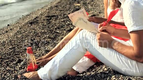 年轻夫妇在海滩上写浪漫的信视频的预览图