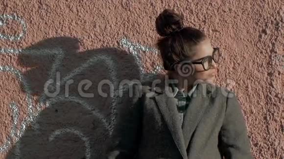 美丽的时尚女性站在城市街道的砖墙附近穿着灰色外套有长发的布鲁内特女孩视频的预览图