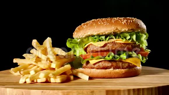 手工牛肉汉堡和炸薯条黑色背景的酱汁快餐食品视频的预览图