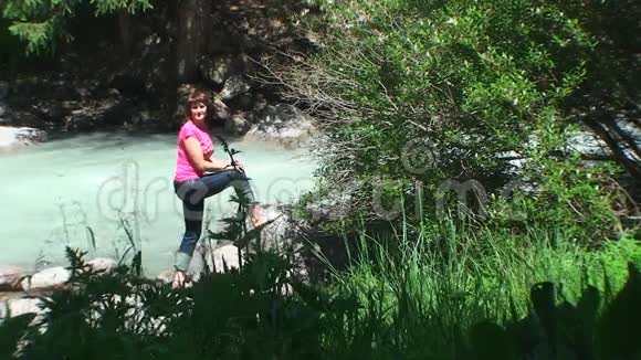 一位年轻女子站在山河的岸边阳光灿烂视频的预览图
