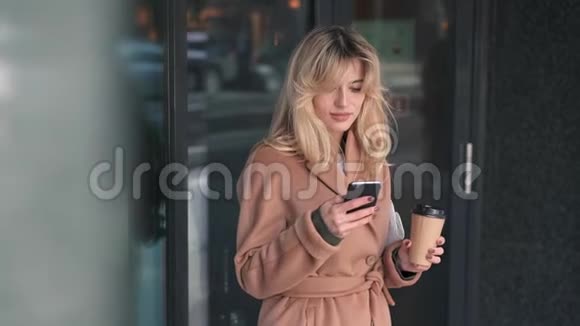 美丽的女人站在外面用智能手机视频的预览图
