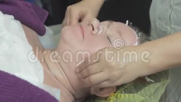 美容师用海藻面膜后的棉垫擦拭美容院女性面部视频的预览图