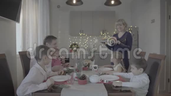欢乐兴奋的六个家庭在节日气氛中庆祝可爱的圣诞晚餐舒适的厨房视频的预览图