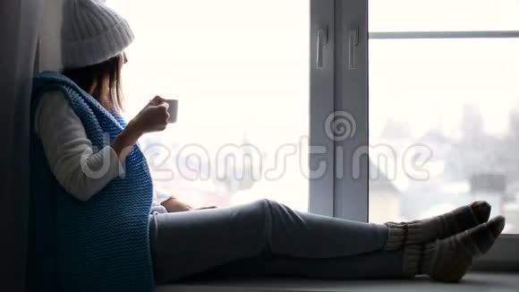 穿着白色帽子和蓝色背心的女孩坐在窗台上视频的预览图