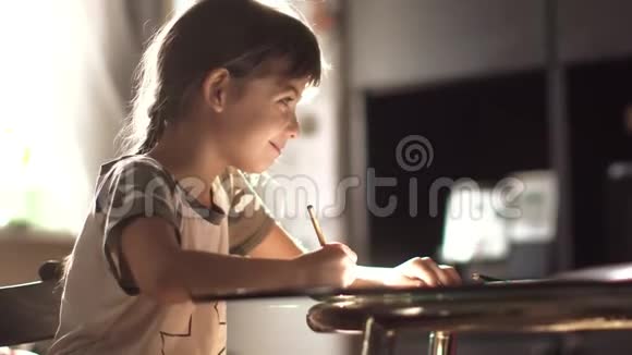 小女孩在家里用铅笔画画坐在桌子旁在朝阳下的孩子视频的预览图