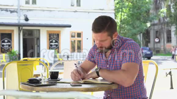 男人在咖啡馆里做笔记从智能手机到笔记本视频的预览图