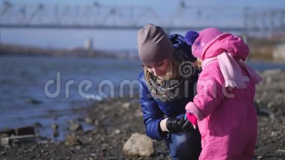 一位年轻的母亲和两个小女儿正走在河的城堤上慢动作视频的预览图