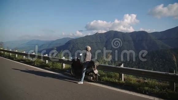 年轻女子在滑板车山路上美丽的风景享受自由的旅行视频的预览图