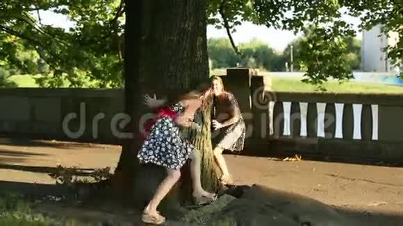 两个年轻的少女在公园里尽情玩耍绕着树跑视频的预览图