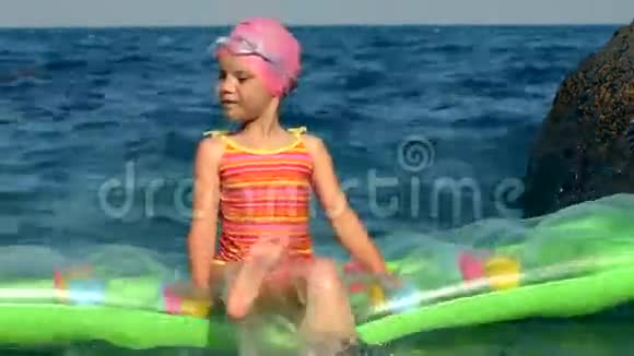 小女孩坐在海中的床垫上视频的预览图