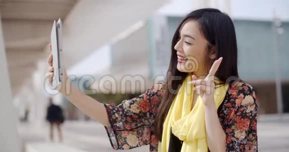开朗的女性为平板相机做手势视频的预览图