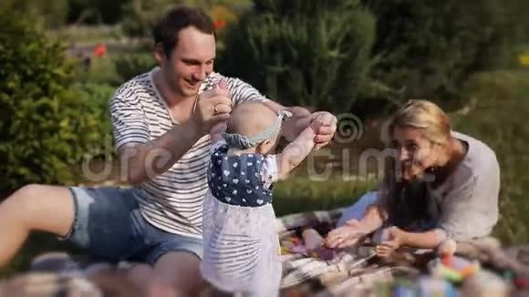 年轻夫妇带着一个孩子在公园草地上休息视频的预览图