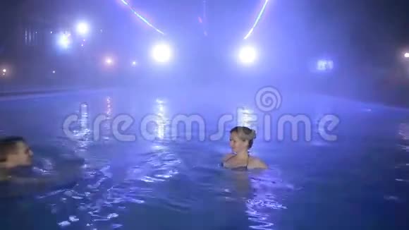 一对男女晚上在一个有热水的游泳池里游泳视频的预览图