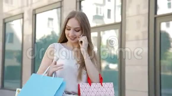 女孩开心地笑着拿着许多购物袋在电话里交谈视频的预览图