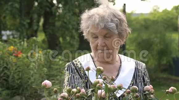 在牡丹生长的背景下的老妇人视频的预览图