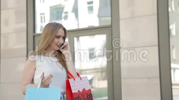 女孩开心地笑着拿着许多购物袋在电话里交谈视频的预览图