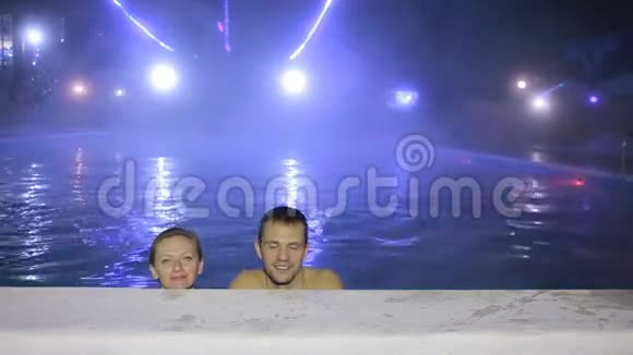 一对男女晚上在一个有热水的游泳池里游泳视频的预览图