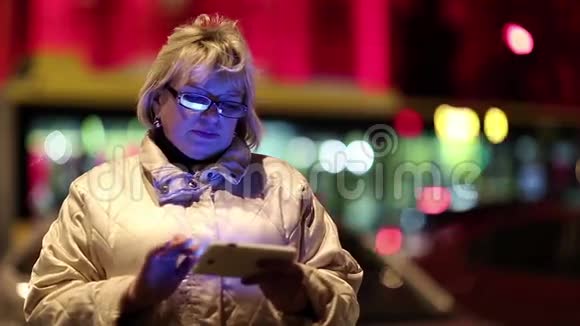 晚上有手机的老妇人站在路边视频的预览图