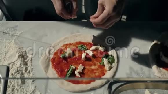 餐厅的厨师准备了一份披萨并用番茄拉和罗勒装饰视频的预览图
