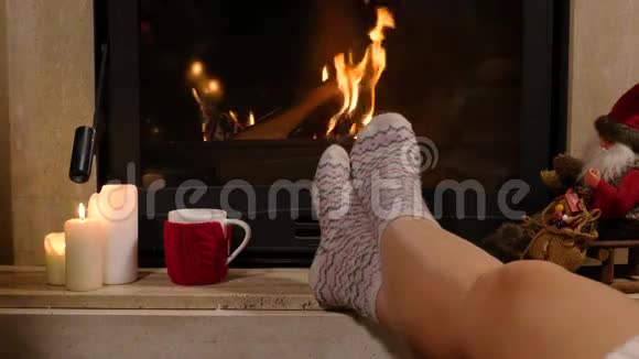 女人坐在壁炉旁端着一杯热饮和一本书视频的预览图