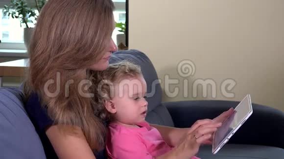 母亲用平板电脑教蹒跚学步的女孩视频的预览图