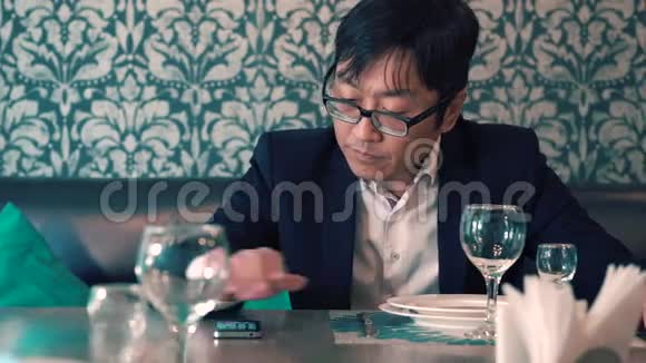穿西装的亚洲男人在咖啡馆里等着他们的食物长时间等待点餐紧张视频的预览图