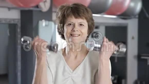 一个成熟的女人举起哑铃年长的健身的视频的预览图