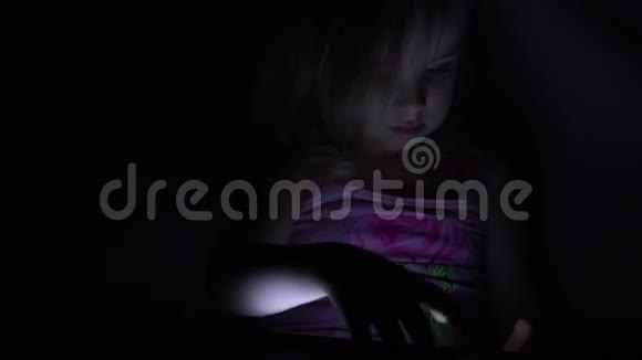 可爱的小女孩在黑暗房间的平板电脑上工作4K超高清超高清视频的预览图
